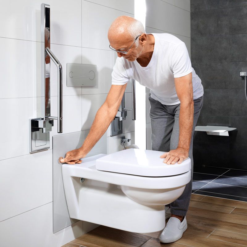 Ein alter Mann stellt die Höhe einer Toilette mit einem einfachen Knopfdruck passend ein.